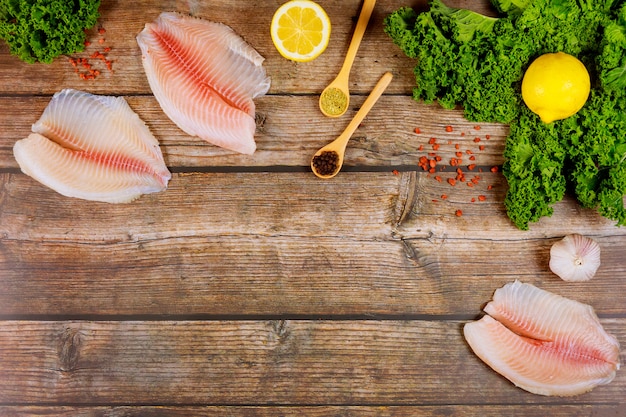 Filetes de tilápia crua com tempero e legumes na mesa rústica