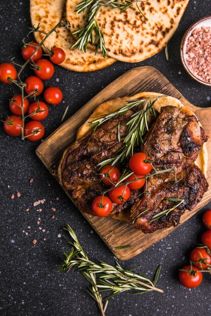 Filetes Filete de carne a la parrilla en rodajas Nueva York o Ribeye con especias, romero y pimienta en tablero negro Vista superior