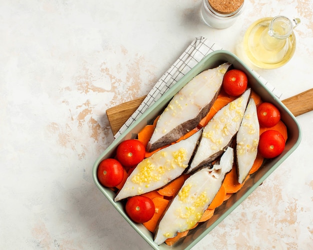 Filetes de fletán refrigerados en una fuente para hornear con tomates y batatas