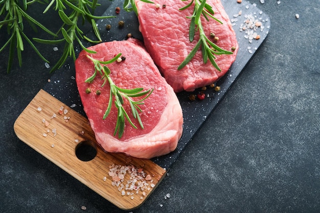 Filetes Fresh Filet mignon Filetes con especias, romero y pimienta sobre tablero de mármol negro sobre fondo gris Vista superior Maqueta