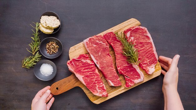 Filetes de lomo crudos de Nueva York en una tabla para cortar madera.