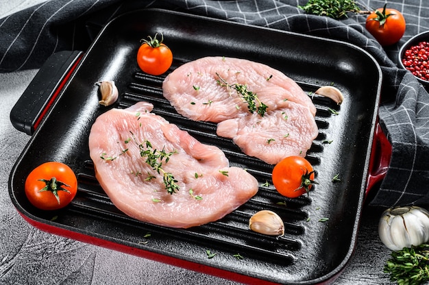 Filetes de pechuga de pavo crudos en una sartén. Carne de ave orgánica. Fondo gris. Vista superior.