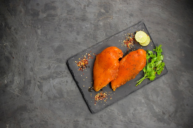 Filetes de pechuga de pollo marinados dispuestos sobre una placa de grafito