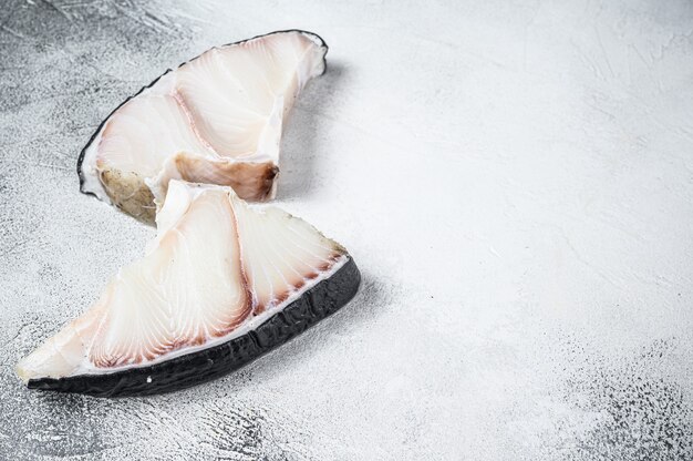 Filetes de pescado crudo de tiburón en una mesa de cocina.