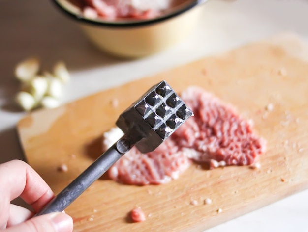 Filetes picados frescos crudos para chuletas y martillo de carne en la tabla de cortar