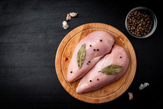 Filetes de pollo crudo sobre fondo negro.