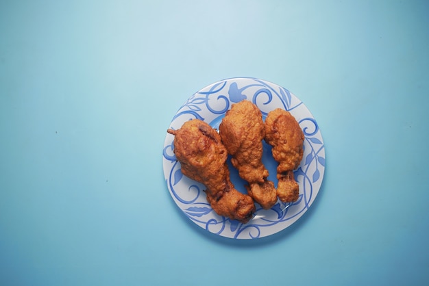 Filetes de pollo frito en la placa sobre la superficie azul