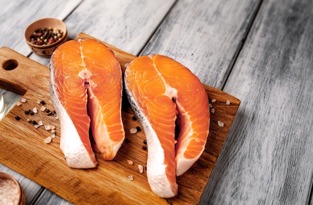 Filetes de salmón crudo con especias, hierbas, sal y limón sobre un fondo de madera con espacio de copia para su texto.