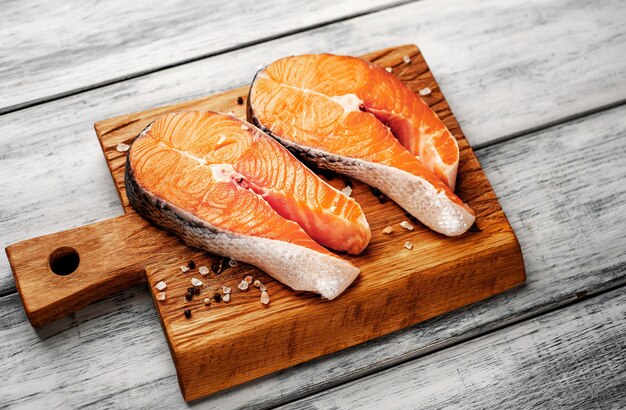 Filetes de salmón crudo con especias, hierbas, sal y limón sobre un fondo de madera.