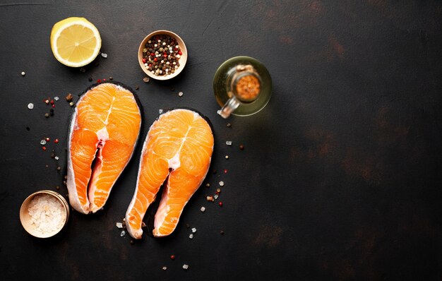 Foto filetes de salmón crudo con especias, hierbas, sal y limón sobre un fondo de piedra con espacio de copia para su texto.