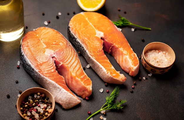 Filetes de salmón crudo con especias, hierbas, sal y limón sobre un fondo de piedra.