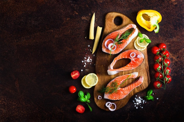 Filetes de salmón crudo hierbas aromáticas cebolla limón sal y verduras frescas para cocinar sobre fondo de madera Copyspace Concepto de alimentos saludables y dietéticos Vista superior Menú de marco de pancarta