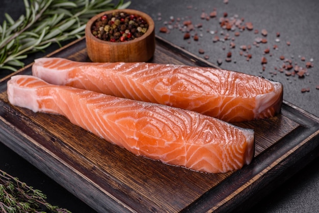 Filetes de salmón fresco en tabla de cortar negra con hierbas y especias