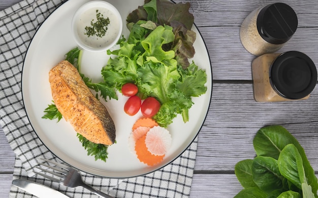 Filetes de salmón frito con verduras en la mesa de madera