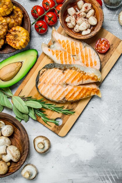 Filetes de salmón a la parrilla con verduras en una tabla de madera