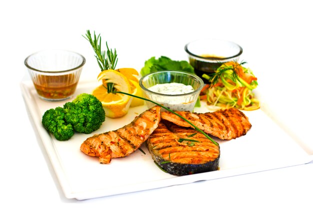 Filetes de salmón a la plancha. Servido con verduras y especias en un plato blanco.