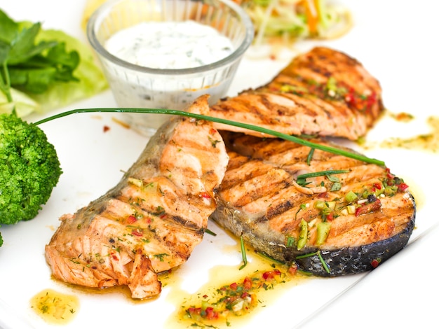 Filetes de salmón a la plancha. Servido con verduras y especias en un plato blanco.