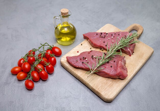 Filetes en una tabla de madera, junto a una ramita de tomates cherry al romero