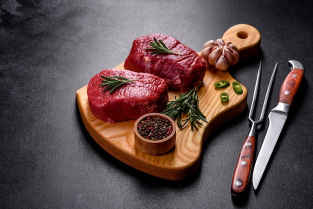 Filetes de ternera cruda en una tabla de cortar con especias sobre un fondo de piedra