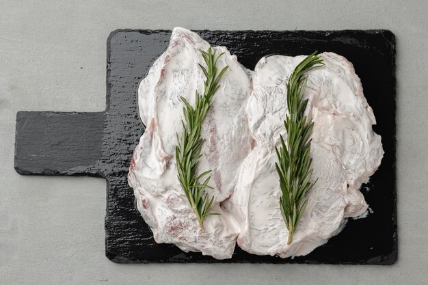 Foto filetes de ternera marinados con romero sobre tablero de piedra negra