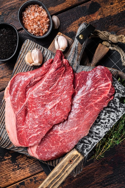 Filetes de ternera de primera calidad, carne cruda con especias en la tabla de cortar del carnicero. Fondo de madera. Vista superior.