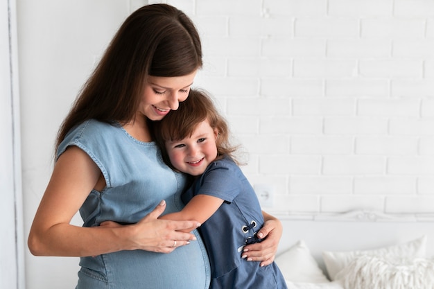 Filha abraçando sua mãe grávida