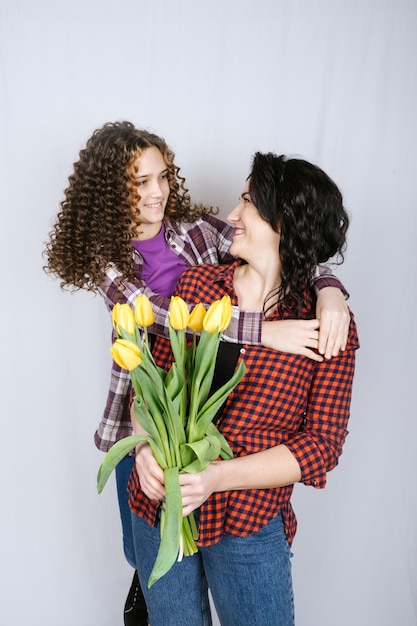 Filha adolescente feliz felicita a mãe no aniversário do feriado e dá flores de presente