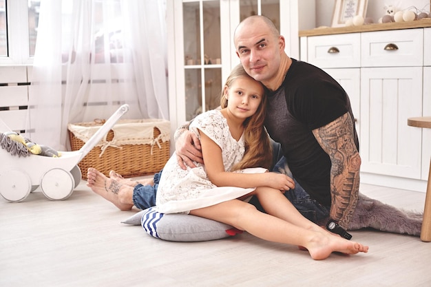 Filha adorável usando um vestido branco com seu pai amoroso em um quarto infantil moderno com um ...