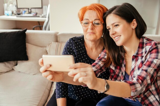 Foto filha adulta com a mãe em casa a tirar uma selfie