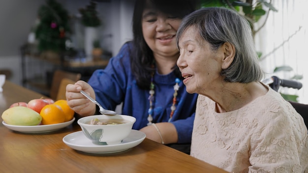 Filha alimentando a mãe idosa com sopa.