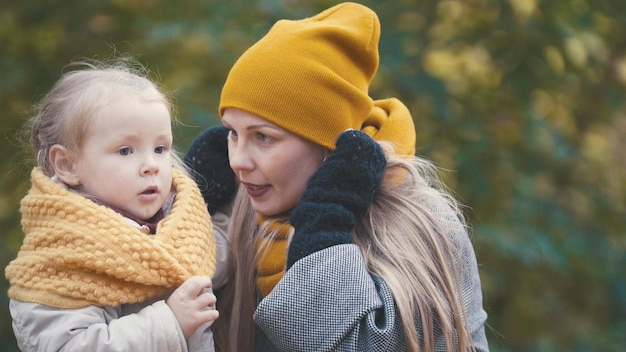 Filha bonita com a mãe caminhando no parque de outono