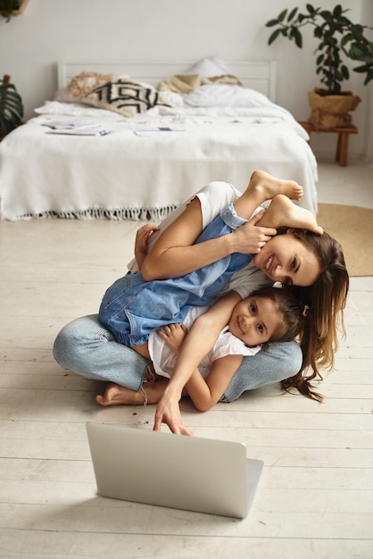 Filha brinca com a mãe e o gato enquanto a mãe trabalha no computador