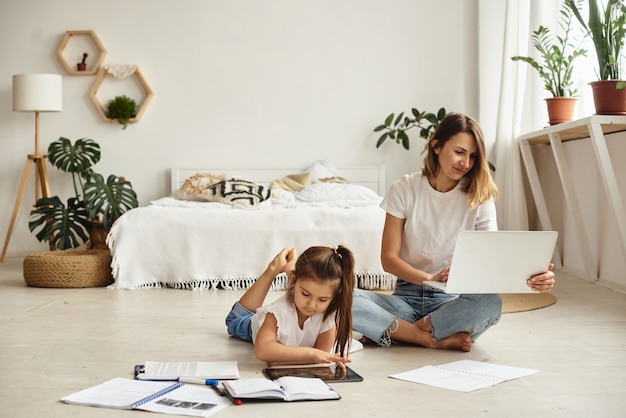 Filha brinca com a mãe e o gato enquanto a mãe trabalha no computador