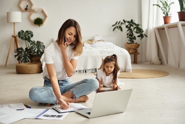 Filha brinca com a mãe e o gato enquanto a mãe trabalha no computador