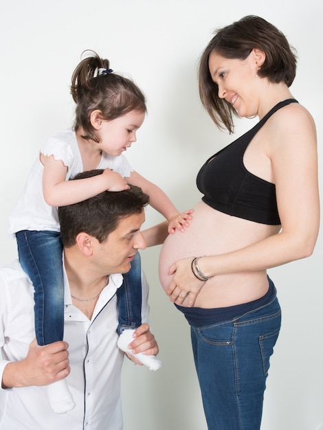 Filha com barriga de mãe grávida brincar com o pai