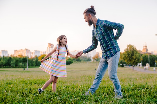 Filha de criança menina segurando a mão do pai no parque