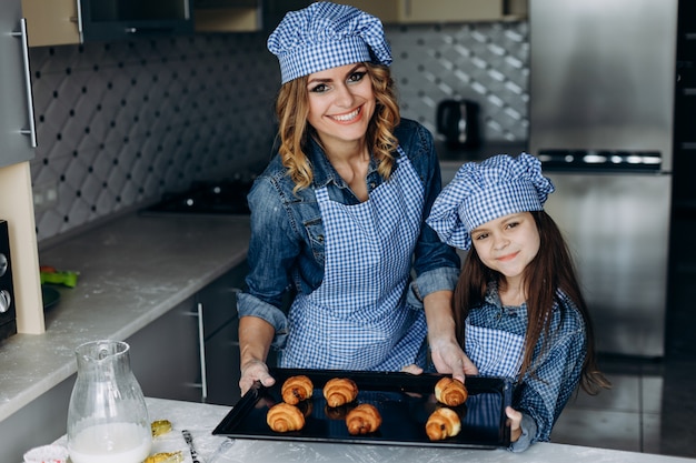 Filha e mãe cozida croissants.Family concept