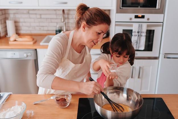 Filha e mãe cozinhando em casa uma sobremesa deliciosa para o dia das mães