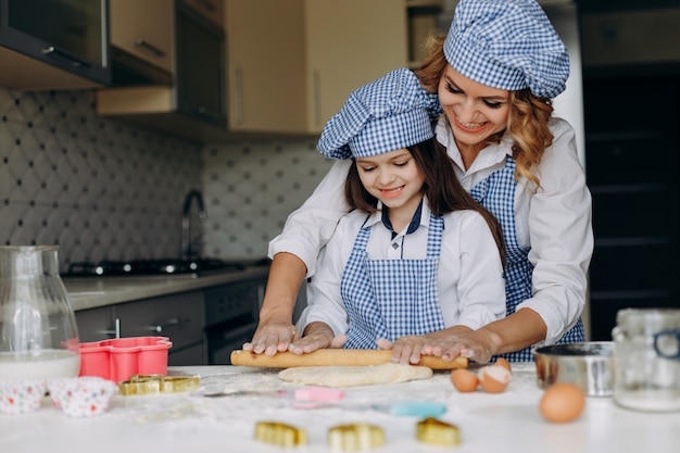 Filha e mãe estender a massa com um rolo juntos. conceito familiar