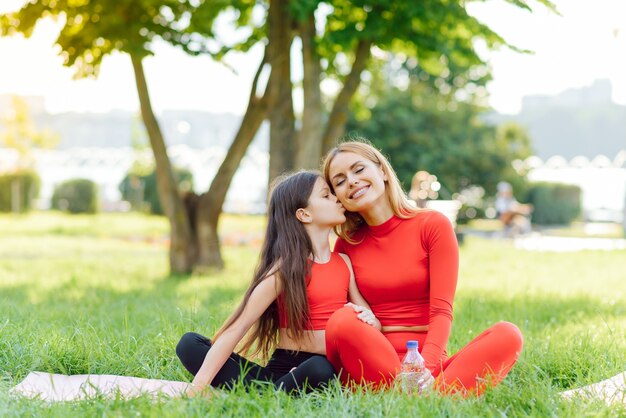 Filha e mãe fofas fazendo exercícios, fitness e ioga no parque matinal