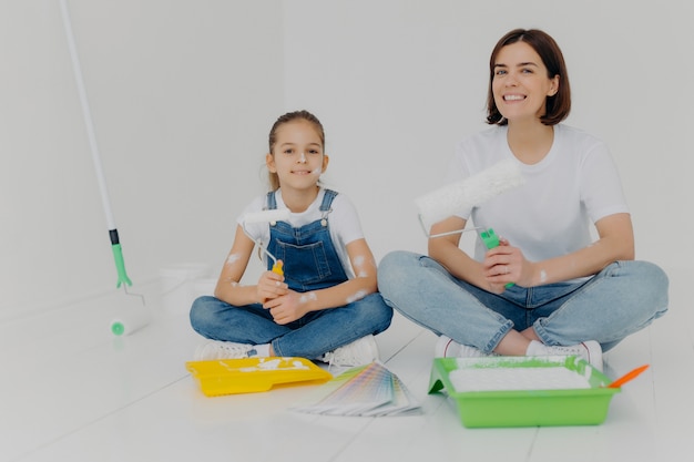 Filha e menina alegre sentar pernas cruzadas no chão