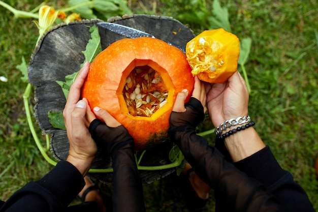 Foto filha e pai abrem as mãos, cortam a abóbora antes de esculpir para o halloween, prepara jack o'lantern. decoração para festa, ajudante de família, vista de cima, close-up, vista de cima, espaço de cópia