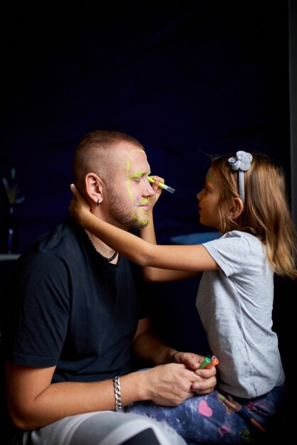 Filha e pai pintam uma cara, se divertindo