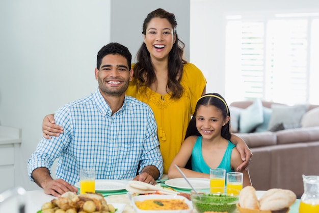 Filha e pais tendo refeição na mesa em casa