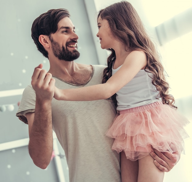 Filha e seu pai jovem e bonito estão dançando.