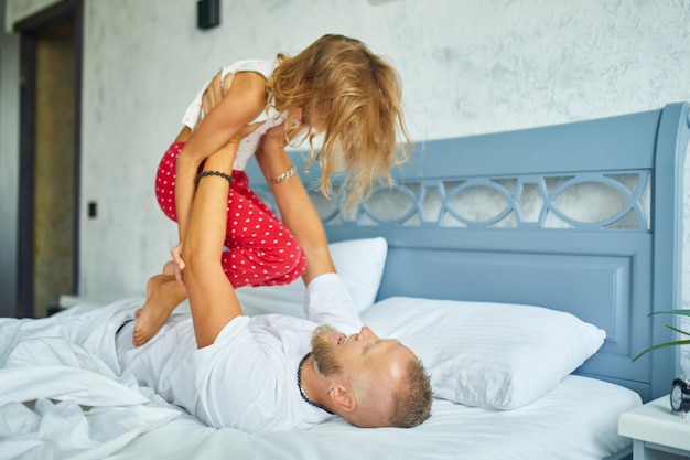 Filha feliz e pai brincando na cama pela manhã em casa