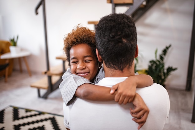 Filha feliz que abraça o pai em casa.