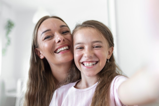 Filha jovem mãe enfrenta webcam close-up vista. garota adorável criança usando smartphone, se divertir com a irmã mais velha fazendo fotos de selfie, vloggers gravam novo vlog, aproveite o conceito de atividade engraçada