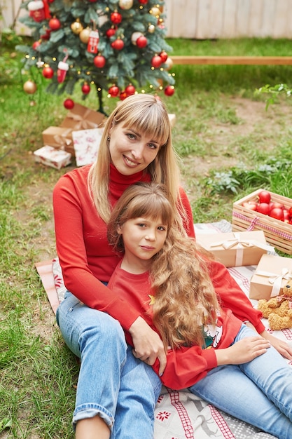 Filha mãe e bebê perto da árvore de Natal com presentes, Natal em família em julho. Férias de inverno e conceito de pessoas. Cartão de feliz Natal e boas festas.