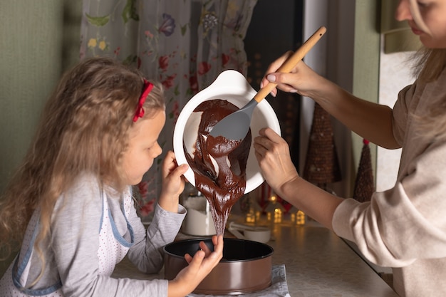 Filha mãe e filha cozinhando bolo de chocolate de natal juntas